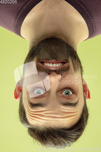 Image of Inverted portrait of caucasian young man on yellow studio background