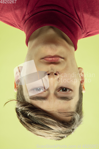 Image of Inverted portrait of caucasian young man on yellow studio background