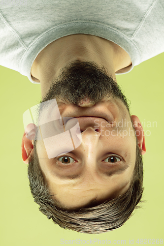 Image of Inverted portrait of caucasian young man on yellow studio background