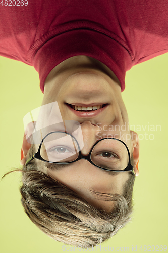 Image of Inverted portrait of caucasian young man on yellow studio background