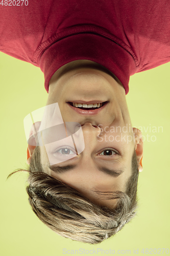 Image of Inverted portrait of caucasian young man on yellow studio background