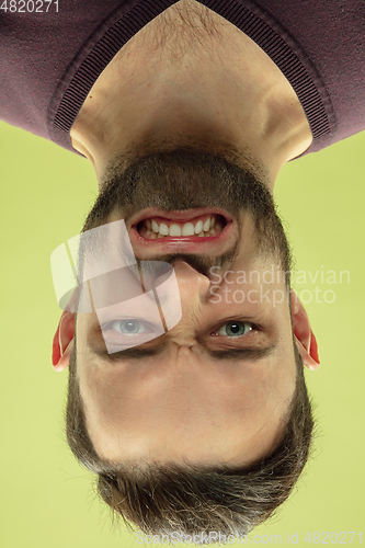 Image of Inverted portrait of caucasian young man on yellow studio background