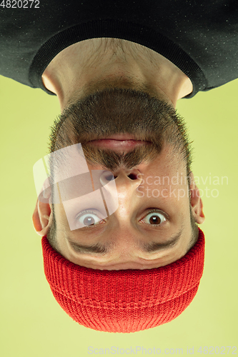 Image of Inverted portrait of caucasian young man on yellow studio background