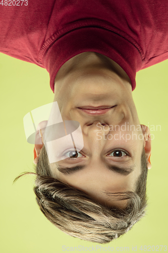 Image of Inverted portrait of caucasian young man on yellow studio background