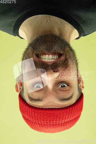 Image of Inverted portrait of caucasian young man on yellow studio background