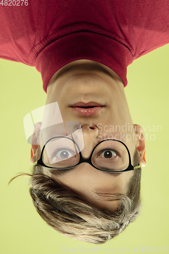 Image of Inverted portrait of caucasian young man on yellow studio background