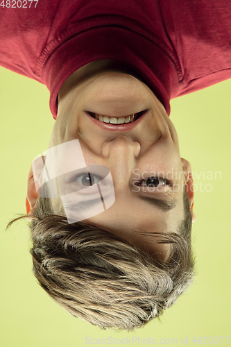 Image of Inverted portrait of caucasian young man on yellow studio background