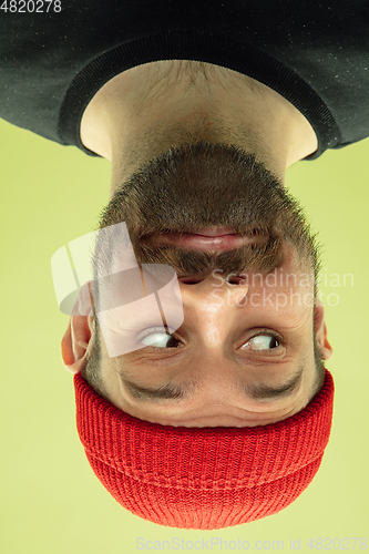 Image of Inverted portrait of caucasian young man on yellow studio background