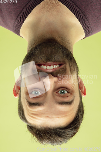 Image of Inverted portrait of caucasian young man on yellow studio background