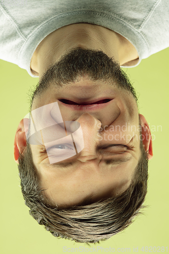 Image of Inverted portrait of caucasian young man on yellow studio background