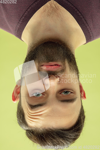 Image of Inverted portrait of caucasian young man on yellow studio background