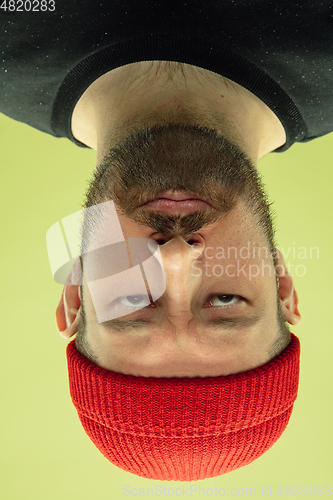 Image of Inverted portrait of caucasian young man on yellow studio background