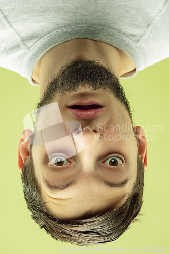 Image of Inverted portrait of caucasian young man on yellow studio background