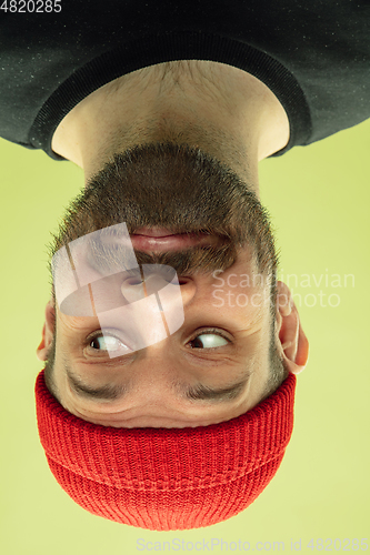 Image of Inverted portrait of caucasian young man on yellow studio background