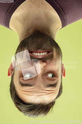 Image of Inverted portrait of caucasian young man on yellow studio background