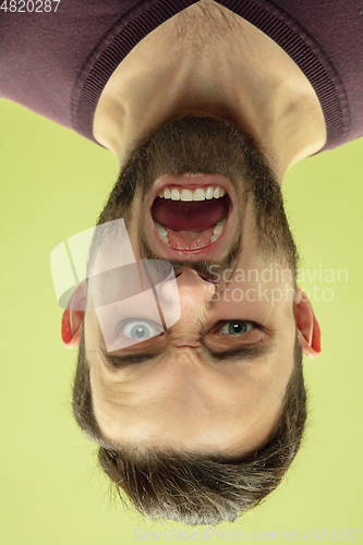 Image of Inverted portrait of caucasian young man on yellow studio background