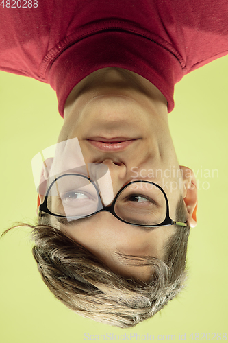 Image of Inverted portrait of caucasian young man on yellow studio background