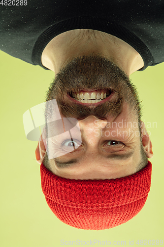 Image of Inverted portrait of caucasian young man on yellow studio background