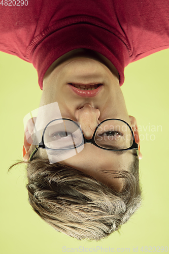 Image of Inverted portrait of caucasian young man on yellow studio background