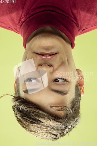 Image of Inverted portrait of caucasian young man on yellow studio background