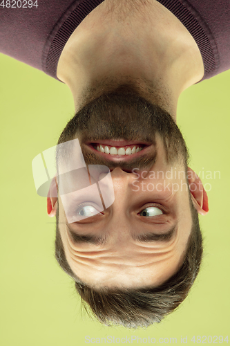 Image of Inverted portrait of caucasian young man on yellow studio background