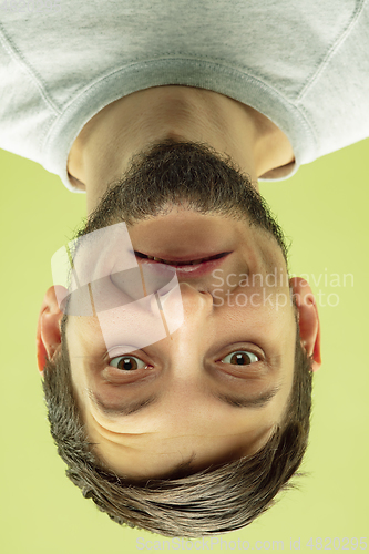 Image of Inverted portrait of caucasian young man on yellow studio background