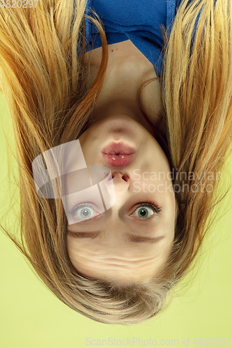 Image of Inverted portrait of caucasian young woman on yellow studio background