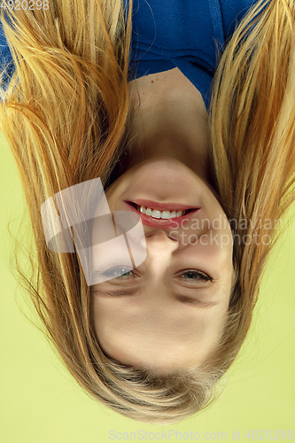 Image of Inverted portrait of caucasian young woman on yellow studio background