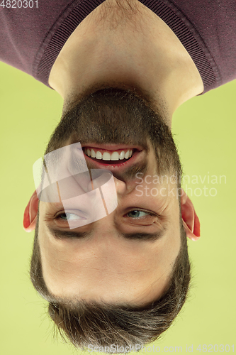 Image of Inverted portrait of caucasian young man on yellow studio background