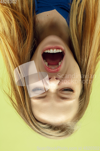 Image of Inverted portrait of caucasian young woman on yellow studio background