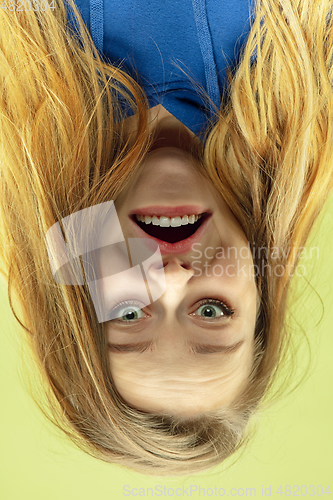 Image of Inverted portrait of caucasian young woman on yellow studio background