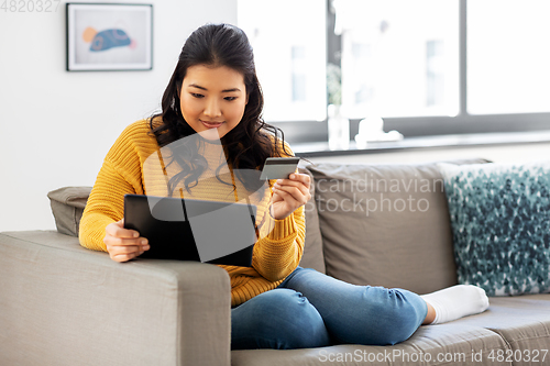 Image of asian woman with tablet pc and credit card at home