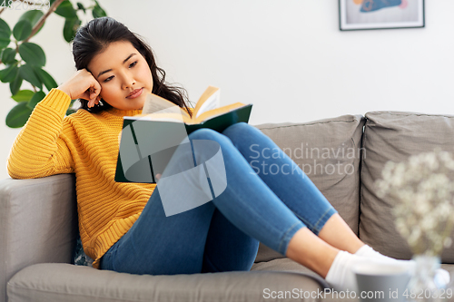 Image of asian young woman reading book at home