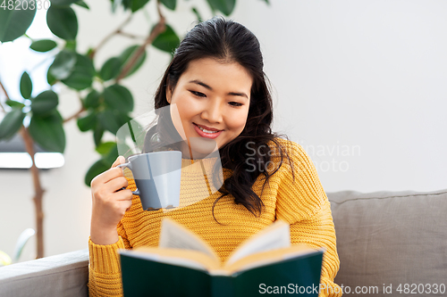 Image of woman reading book and drinking coffee at home