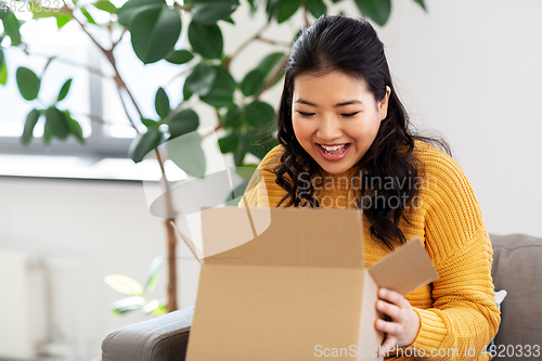 Image of happy asian young woman with parcel box at home