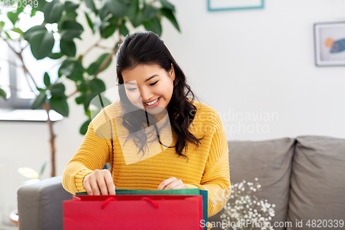 Image of asian young woman with shopping bag at home