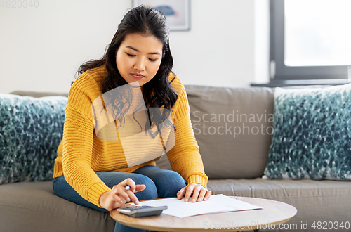 Image of asian woman with papers and calculator at home