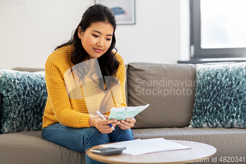 Image of woman with money, papers and calculator at home