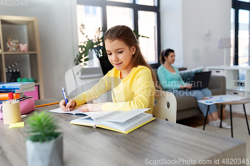 Image of student girl with book writing to notebook at home