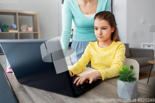 Image of mother and daughter with laptop doing homework