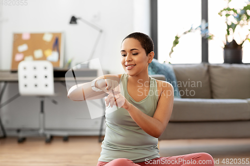 Image of woman with smart watch doing sports at home