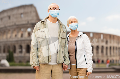 Image of senior couple in protective medical masks in italy