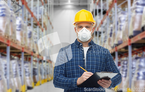 Image of male worker in mask with clipboard at warehouse