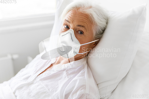 Image of old woman in respirator lying in bed at hospital