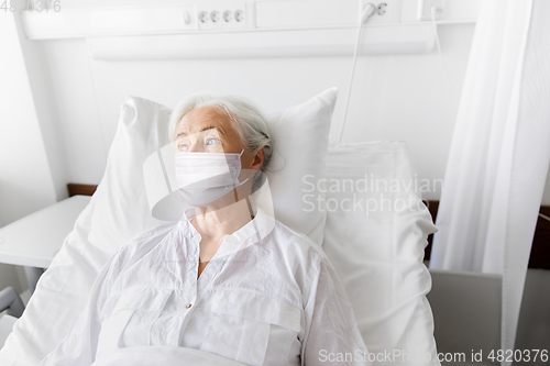 Image of old woman patient in mask lying in bed at hospital