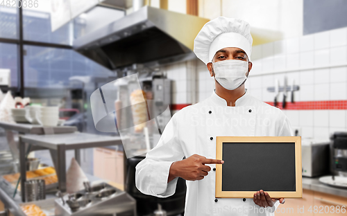 Image of chef in face mask with chalkboard at kitchen