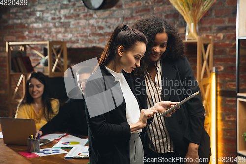 Image of Colleagues working together in modern office using devices and gadgets during creative meeting