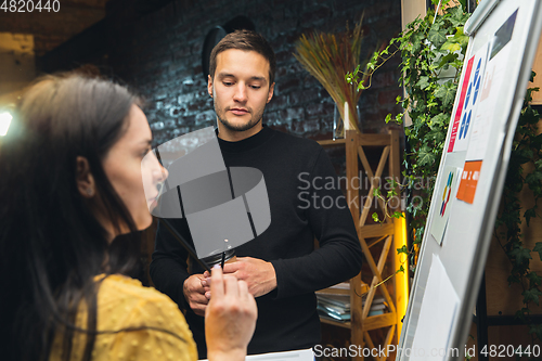 Image of Colleagues working together in modern office using flipchart during creative meeting