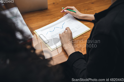 Image of Close up hands of people, managers working in modern office using modern devices and flipchart with graphics