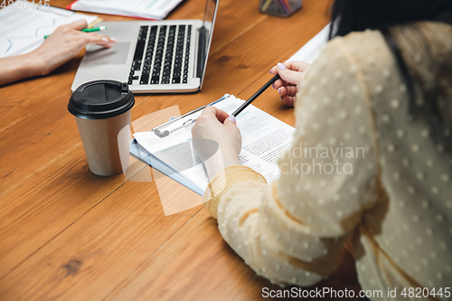 Image of Close up hands of people, managers working in modern office using modern devices and flipchart with graphics